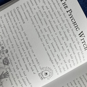 May include: A book cover with the title "The Psychic Witch" in black text. The cover features a black and white illustration of a crystal ball with an eye inside. The text below the title reads "How many witches have their attention brought to the magickal side of life by coincidences which really feel like so much more?"
