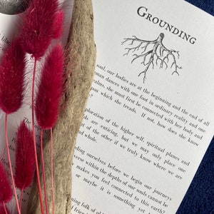 May include: A book with the word "Grounding" printed on the cover. The book is open to a page with a black and white illustration of a tree with roots. The text on the page discusses the concept of grounding and how it relates to the higher self.