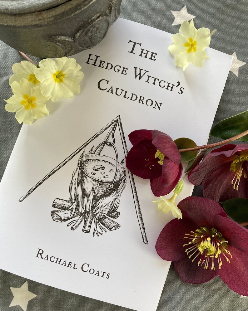 May include: A white book with black text that reads "The Hedge Witch's Cauldron" and "Rachael Coats". The book features a black and white illustration of a cauldron hanging over a fire.