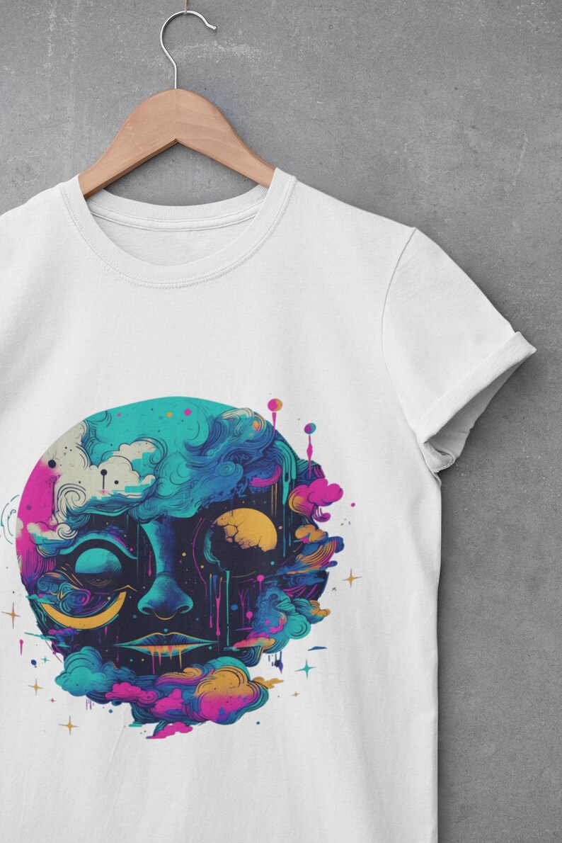 Puede incluir: Camiseta blanca con un estampado gr&aacute;fico colorido de una cara rodeada de nubes y estrellas. La cara est&aacute; compuesta por colores azules, rosas, amarillos y morados.