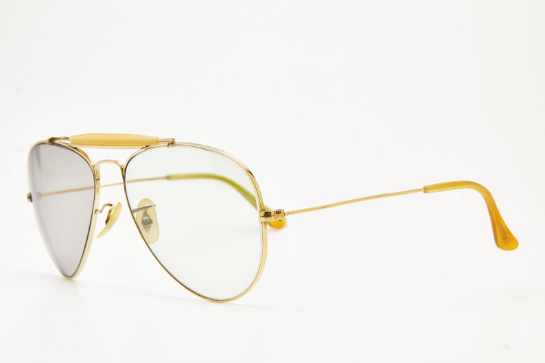 Puede incluir: Gafas de sol aviador con montura dorada, puente y patillas en marr&oacute;n claro. Las lentes son de color plateado degradado. Dise&ntilde;o cl&aacute;sico, adecuadas para diferentes estilos.