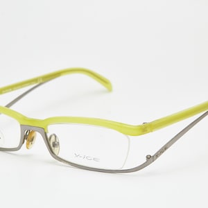 Puede incluir: Gafas con montura superior y patillas verde lima, y montura inferior plateada. Las lentes son transparentes y las gafas tienen un diseño moderno y semi-sin montura. La marca "X-ICE" es visible en la montura.