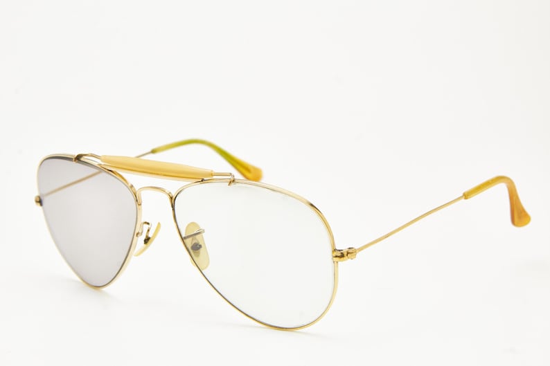 Puede incluir: Gafas de sol aviador con montura dorada y lentes espejadas plateadas. Las gafas de sol tienen una barra de puente y patillas con detalles amarillos y verdes. Un accesorio de gafas cl&aacute;sico.