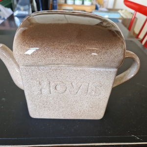 Może przedstawiać: Brązowy ceramiczny czajnik w kształcie bochenka chleba z wytłoczonym napisem "HOVIS" z przodu.