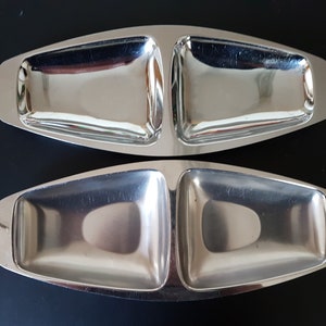 May include: Two silver serving trays with two divided compartments. The trays are made of stainless steel and have a shiny finish.
