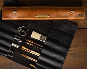 May include: A brown leather artist's brush roll with a matching case. The roll is open, revealing various art tools, including brushes, scissors, and other implements. The case has the text "Your Name Here".