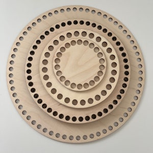 May include: Set of three round wooden knitting looms with different sizes. The looms are made of natural wood and have holes around the edges for knitting.