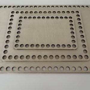 Könnte beinhalten: Drei ineinander verschachtelte quadratische Metallrahmen mit runden Löchern an den Rändern. Die Rahmen sind aus hellem Silbermetall gefertigt und übereinander gestapelt.