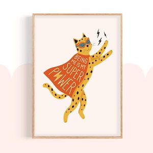 May include: A framed art print featuring a yellow cheetah with black spots, wearing a superhero mask and cape. The orange cape reads "Being Me Is My Super Power." The cheetah is depicted with raised arms and lightning bolts.