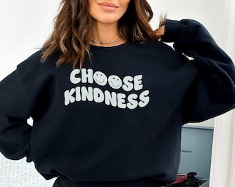 Könnte beinhalten: Schwarzer Pullover mit dem Text "CHOOSE KINDNESS" in Weiß mit zwei Smileys.