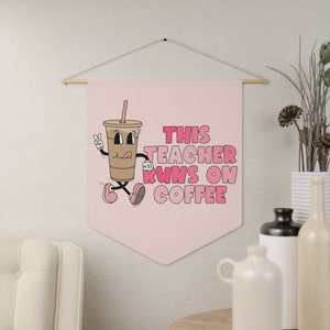Może przedstawiać: Różowo-biały baner z postacią kreskówkowej filiżanki kawy i tekstem "THIS TEACHER RUNS ON COFFEE".