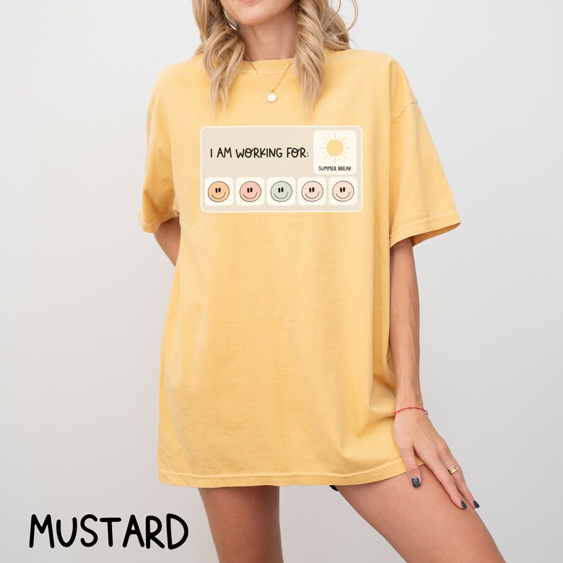 May include: A mustard yellow t-shirt with the text "I am working for: Summer Break" and a graphic of a sun and a row of six smiley faces.