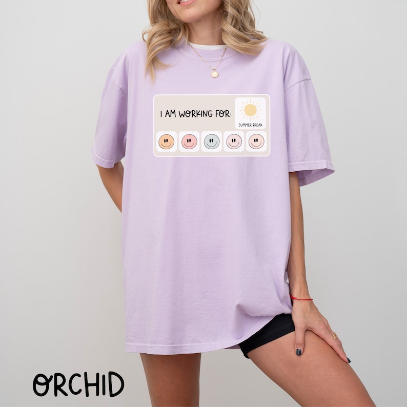 May include: A lavender t-shirt with the text "I am working for: Summer Break" and a graphic of a sun and six smiley faces.