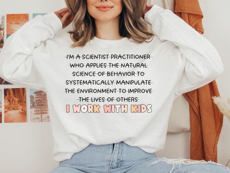 May include: White sweatshirt with the text "I'm a scientist practitioner who applies the natural science of behavior to systematically manipulate the environment to improve the lives of others I work with kids".