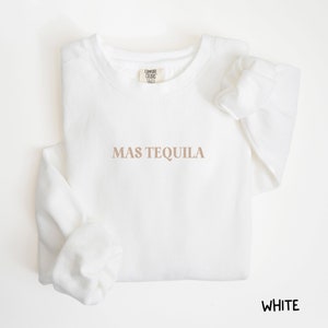 May include: White crewneck sweatshirt with the text "MAS TEQUILA" printed in brown on the front.