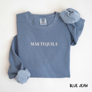May include: A blue jean sweatshirt with the text "MAS TEQUILA" in white lettering.