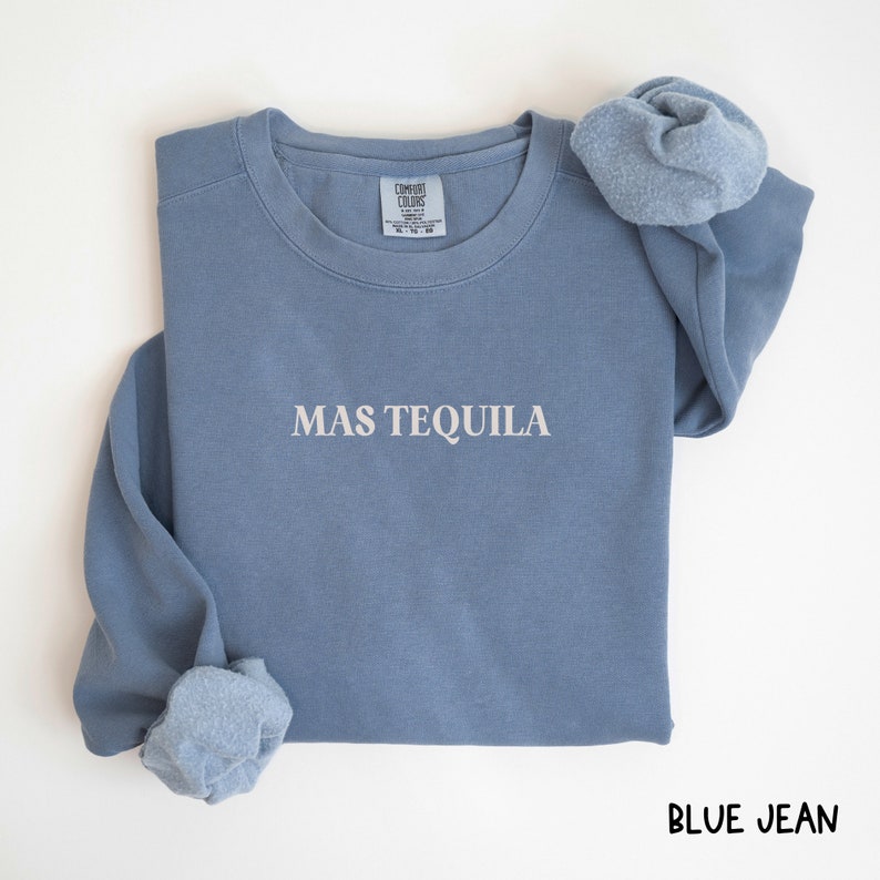 May include: A blue jean sweatshirt with the text "MAS TEQUILA" in white lettering.