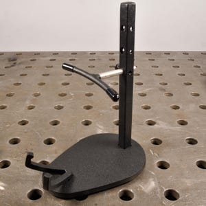 May include: Black metal guitar stand with a curved arm and a round base. The stand is designed to hold a guitar upright.
