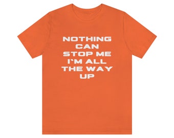 May include: Orange t-shirt with the text "NOTHING CAN STOP ME I'M ALL THE WAY UP" in white.