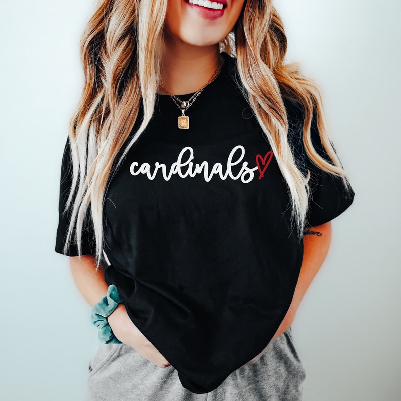 May include: Black t-shirt with white text that says "cardinals" and a red heart.