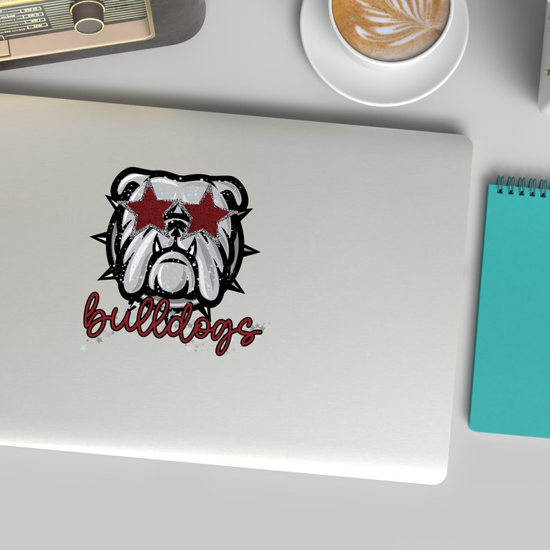 K&ouml;nnte beinhalten: Ein wei&szlig;er Bulldogge mit roten sternf&ouml;rmigen Sonnenbrillen und einem silbernen Glitzer-Effekt. Der Text "bulldogs" ist in rot unter dem Bulldogge geschrieben.