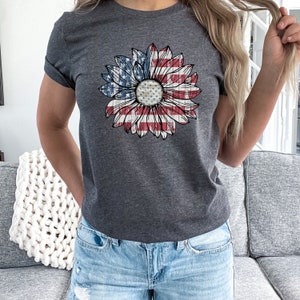 Może przedstawiać: Szary t-shirt z nadrukiem w postaci spękanego słonecznika w barwach amerykańskiej flagi.