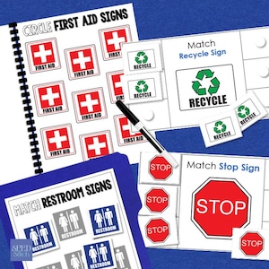 May include: Educational matching game with various signs. Includes a spiral-bound notebook with "CIRCLE FIRST AID SIGNS" and red cross symbols. Also features "RECYCLE", "STOP", and "RESTROOM" signs. A black and white pen is included.