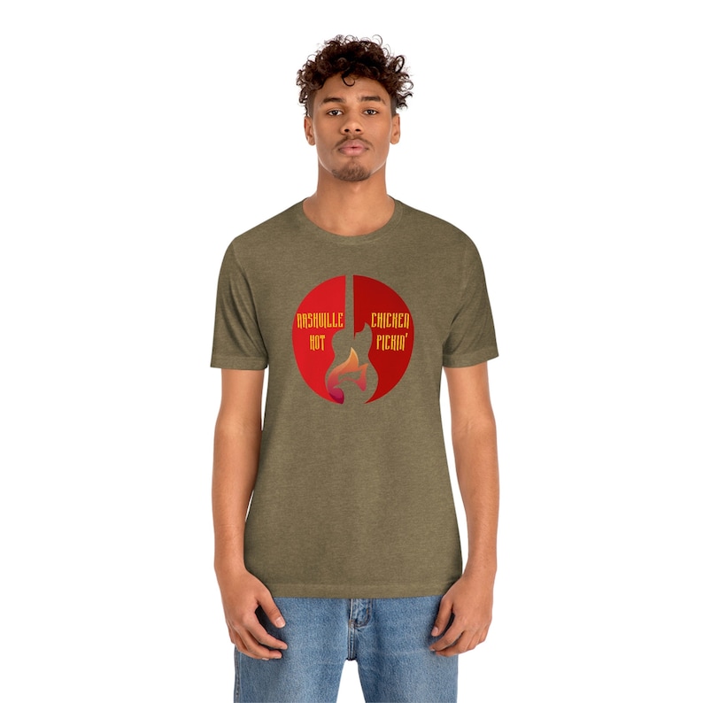 以下が含まれることがあります： 赤い円形のグラフィックが描かれた緑色のTシャツ。グラフィックは、ギターのシルエットで、左側に「Nashville Hot」、右側に「Chicken Picin'」というテキストが書かれています。