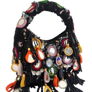 May include: A black beaded handbag with a curved handle. The bag is decorated with colourful embellishments, including mirrors, tassels, and sequins. The handle has red, green, and pink accents.