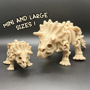 May include: Two beige triceratops dinosaur skeleton models, one small and one large, are displayed against a dark background. The larger model has detailed bone structure. Text in the image reads "MINI AND LARGE SIZES!"