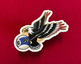 May include: A sticker featuring a cartoon bald eagle with red, white, and blue feathers holding a blue and white billiard ball with the number 10 on it.
