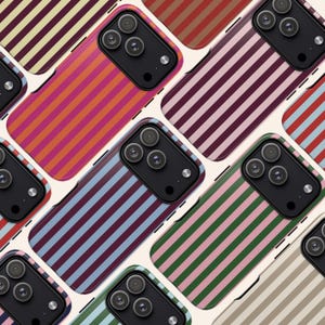 May include: A collection of smartphone cases with colorful, vertical striped patterns. The cases feature a variety of color combinations, including orange and pink, blue and burgundy, and green and pink. The cases have a black camera module.