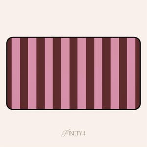 May include: A rectangular design with rounded corners features alternating vertical stripes of pink and dark brown. The design is set against a cream-colored background. The word "NINETY4" is written in a cursive font at the bottom.
