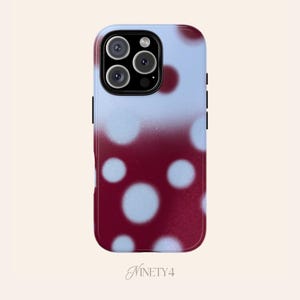Op de afbeelding: Een smartphonehoesje met een gradiëntontwerp. De bovenkant is lichtblauw, overgaand in een dieprode kleur aan de onderkant. Grote witte stippen zijn verspreid over het oppervlak. De hoes heeft een camera-uitsparing en de tekst "NINETY4" onderaan.