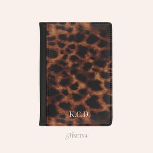 May include: A handmade, ceramic mug with a unique, textured surface. The mug features a speckled, cream-colored glaze with a dark brown rim and handle. The mug is approximately 4 inches tall.