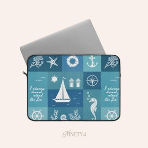 Op de afbeelding: Een laptoptas met een nautisch thema. Het blauw-witte ontwerp toont een zeilboot, anker, zeester en de tekst "I always dream about the sea". De tas is rechthoekig en heeft een zwarte ritssluiting.