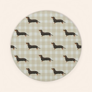 May include: Round beige and white checkered coaster with a repeating pattern of brown dachshund dogs. The coaster is a light beige color with a gingham pattern.