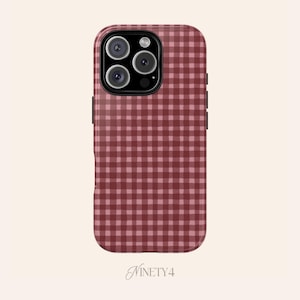 May include: A burgundy and pink gingham patterned phone case. The case has a camera module with three lenses and a flash. The brand name "Ninety4" is printed at the bottom of the case.