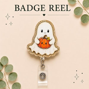 May include: A badge reel featuring a white ghost character holding an orange pumpkin with a smiling face. The ghost has a gold glitter border and is attached to a clear plastic strap and metal clip. The text BADGE REEL is printed above the ghost.