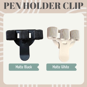 Op de afbeelding: Twee penhouderclips, één matzwart en één matwit. Elke clip heeft drie pennensleuven en een clip om aan een notitieboek of map te bevestigen. De tekst "PEN HOLDER CLIP" staat bovenaan de afbeelding, met "Matte Black" en "Matte White" eronder.
