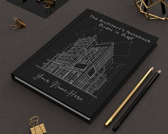 Może przedstawiać: Czarny notatnik z białym projektem architektonicznym i tekstem "The Architect's Notebook Dreams in Draft" i "Your Name Here." Widoczne są również złote i czarne ołówki oraz złote spinacze do papieru.