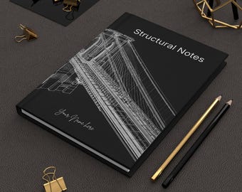 Może przedstawiać: Czarny notatnik z napisem "Structural Notes" i ilustracją mostu. Notatnik ma napis "Your Name Here" na okładce. Widoczne są również złote i czarne ołówki oraz złote spinacze do papieru.