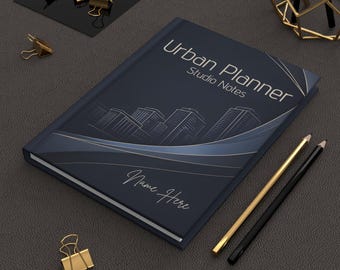 Może przedstawiać: Granatowy notatnik Urban Planner Studio Notes z motywem panoramy miasta i napisem "Name Here". Obecne są również złote i czarne ołówki oraz złote spinacze do papieru.
