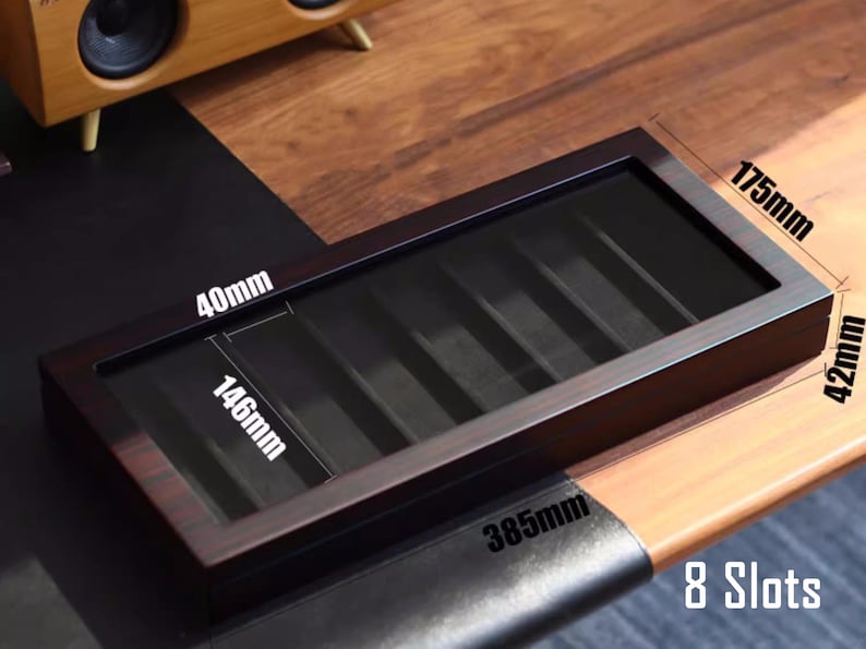 May include: A dark brown wooden box with 8 slots for storing items. The box measures 37 cm long, 10.7 cm wide, and 4 cm tall. The box has a clear plastic lid.