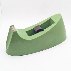 May include: A green plastic tape dispenser with a black tape roll holder.