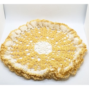 May include: A yellow crocheted doily with a white center and a scalloped edge.