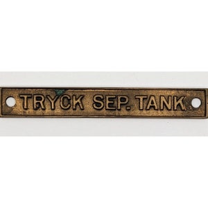 Puede incluir: Una etiqueta rectangular de latón con bordes redondeados y dos agujeros. La etiqueta está grabada con el texto "TRYCK SEP. TANK".