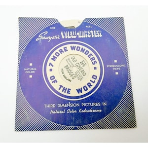 May include: A square blue and white paper sleeve for a Sawyer's View-Master reel. The text reads 7 More Wonders of the World, Old Covered Bridges, New England, and Third Dimension Pictures in Natural Color Kodachrome with stereoscopic views.