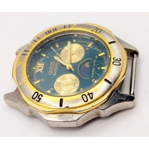 Op de afbeelding: Een gouden en zilveren Guess-horloge met een blauwe wijzerplaat en een datumavenster. Het horloge heeft een maanfase-complicatie en een dag van de week-indicator.