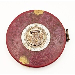 May include: A vintage red tape measure with a silver metal casing. The casing has the text "The Lufkin Rule Co." and "White 100 ft." printed on it.